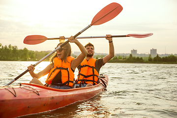 Image showing Happy couple kayaking on river with sunset on the background