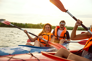 Image showing Happy friends kayaking on river with sunset on the background