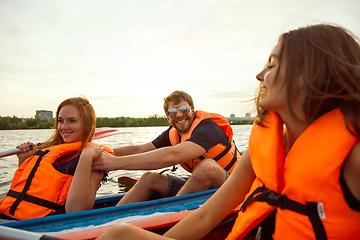 Image showing Happy friends kayaking on river with sunset on the background