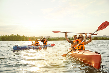 Image showing Happy friends kayaking on river with sunset on the background