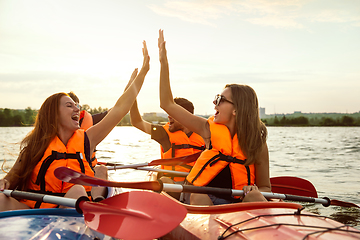 Image showing Happy friends kayaking on river with sunset on the background