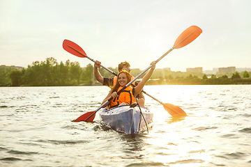 Image showing Happy couple kayaking on river with sunset on the background