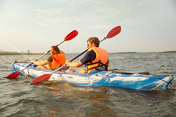 Image showing Happy couple kayaking on river with sunset on the background