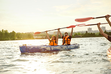 Image showing Happy couple kayaking on river with sunset on the background