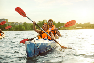 Image showing Happy couple kayaking on river with sunset on the background