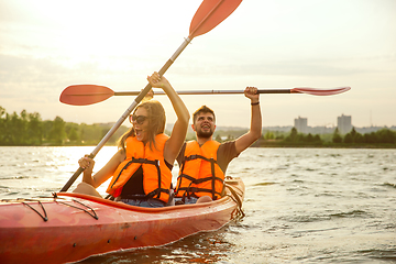 Image showing Happy couple kayaking on river with sunset on the background