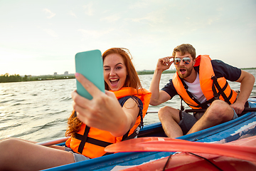 Image showing Happy couple kayaking on river with sunset on the background