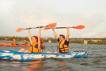 Image showing Happy friends kayaking on river with sunset on the background