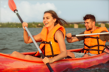 Image showing Happy couple kayaking on river with sunset on the background