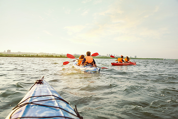 Image showing Happy friends kayaking on river with sunset on the background