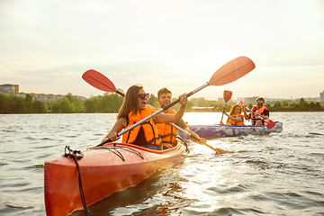 Image showing Happy friends kayaking on river with sunset on the background