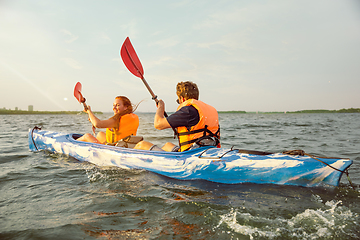 Image showing Happy couple kayaking on river with sunset on the background