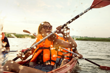 Image showing Happy friends kayaking on river with sunset on the background