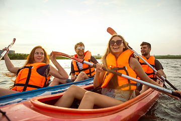 Image showing Happy friends kayaking on river with sunset on the background