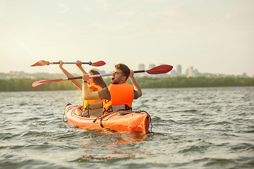 Image showing Happy couple kayaking on river with sunset on the background