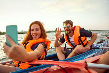 Image showing Happy couple kayaking on river with sunset on the background