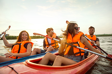 Image showing Happy friends kayaking on river with sunset on the background