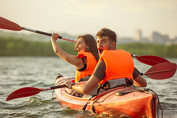 Image showing Happy couple kayaking on river with sunset on the background