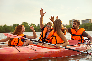 Image showing Happy friends kayaking on river with sunset on the background