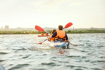 Image showing Happy friends kayaking on river with sunset on the background