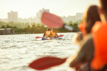 Image showing Happy couple kayaking on river with sunset on the background