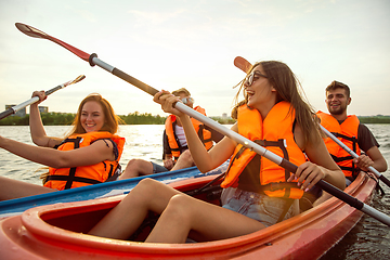 Image showing Happy friends kayaking on river with sunset on the background