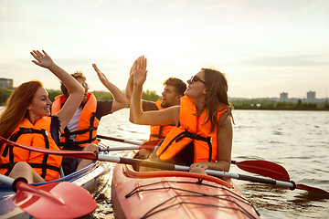 Image showing Happy friends kayaking on river with sunset on the background