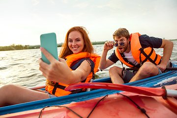 Image showing Happy couple kayaking on river with sunset on the background