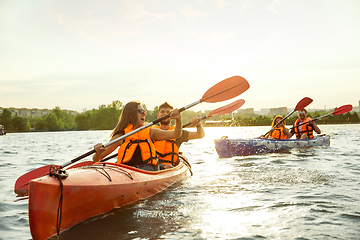 Image showing Happy friends kayaking on river with sunset on the background