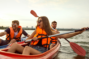 Image showing Happy friends kayaking on river with sunset on the background