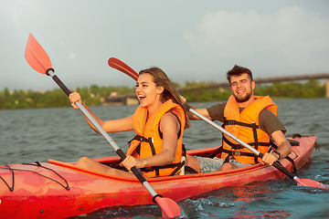 Image showing Happy couple kayaking on river with sunset on the background