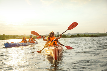 Image showing Happy friends kayaking on river with sunset on the background