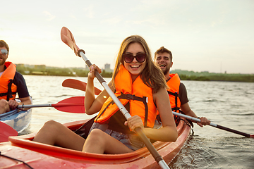 Image showing Happy friends kayaking on river with sunset on the background