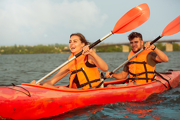 Image showing Happy couple kayaking on river with sunset on the background