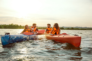 Image showing Happy friends kayaking on river with sunset on the background