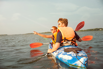 Image showing Happy couple kayaking on river with sunset on the background