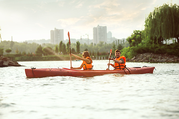 Image showing Happy couple kayaking on river with sunset on the background