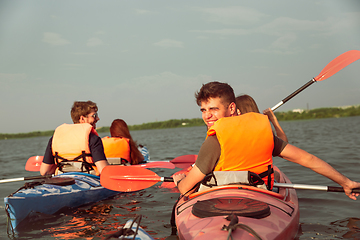 Image showing Happy friends kayaking on river with sunset on the background