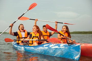 Image showing Happy friends kayaking on river with sunset on the background