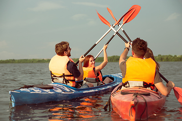 Image showing Happy friends kayaking on river with sunset on the background