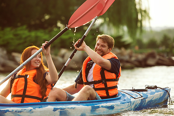 Image showing Happy couple kayaking on river with sunset on the background