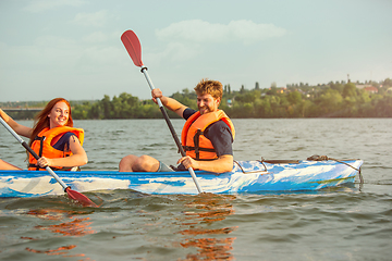 Image showing Happy couple kayaking on river with sunset on the background