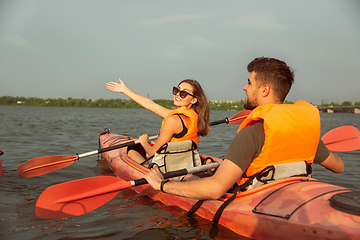 Image showing Happy couple kayaking on river with sunset on the background