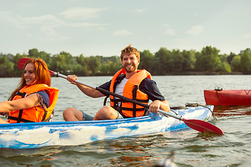 Image showing Happy couple kayaking on river with sunset on the background