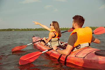 Image showing Happy couple kayaking on river with sunset on the background