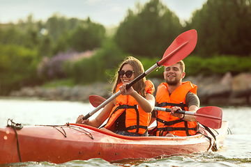 Image showing Happy couple kayaking on river with sunset on the background