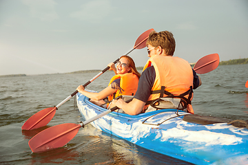 Image showing Happy couple kayaking on river with sunset on the background