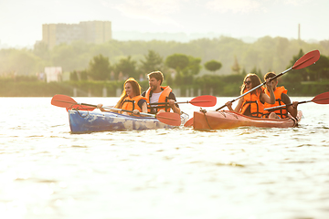 Image showing Happy friends kayaking on river with sunset on the background