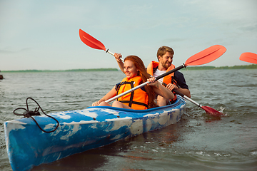 Image showing Happy couple kayaking on river with sunset on the background