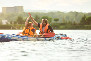 Image showing Happy couple kayaking on river with sunset on the background